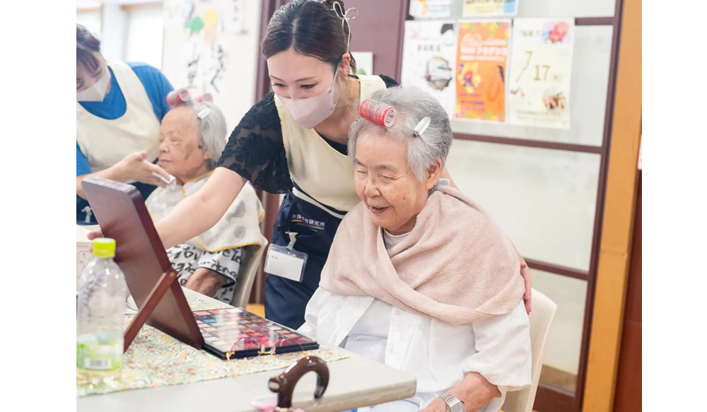高齢女性が美容ケア（ネイルやハンドケアなど）を受けている様子のイメージ画像。<br />
